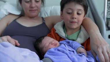 Kardeşi, yeni doğan bebeğe sevgiyle bakar. Annesinin yanında oturur. Kardeşler ve ömür boyu sürecek bir ilişkinin başlangıcı arasındaki hassas bağı vurgular.