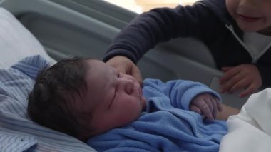 Kardeşi hastanede yeni doğan erkek kardeşiyle kesişiyor. Doğumdan sonra yatakta dinleniyor. Ailenin yeni üyesinin ilk günleri.