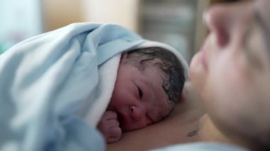 Doğumdan hemen sonra annesinin göğsünde dinlenen yeni doğan bebek, doğumdan sonra hastane kliniğinde gerçek anne bakımı sahnesi.