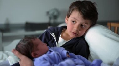 Hastanedeki yeni doğan kardeşimizi selamlayan çocuk - Yaşamın ilk gününü ailece kutluyoruz. Bebek doğduktan sonra ilk kez kardeşler klinikte buluşuyor.