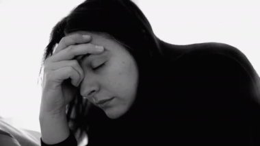 Monokrom portrede duygusal sorunlarla boğuşan bir kadının dramatik yakın plan yüzü. 30 'lu yaşlarda gözleri kapalı ve elleri acı içinde.