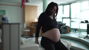 Hastane yatağının yanında oturan hamile bir kadın doğum sancıları sırasında kasılmalar yaşıyor. 30 'lu yaşlarda doğum sırasında acı çeken bir kadın bekliyor.