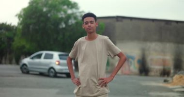 Bir şehir sokağında elleri kalçalarında duran genç bir çocuk, kendine güveni, bireyselliği ve rahat bir tutum sergiliyor.