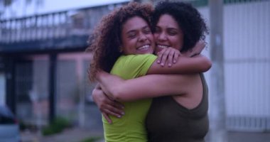 Afrika kökenli anne ve kızı sımsıkı sarılıyor, açık havada samimi ve iç açıcı bir aile anında parlak gülücüklerle sevgisini ve bağlantısını ifade ediyor.