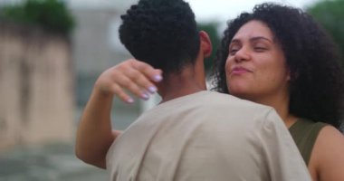 Anne, genç oğlunu neşeli bir gülümsemeyle kucaklıyor ve onu yanağından öpüyor. Şefkatli bir anı paylaşıyor. Açık havada derin bir aile bağı kuruyor.