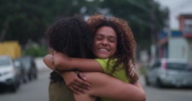 Genç kız, banliyöde bir sokakta annesine sımsıkı sarılıyor. Sevgisini, neşesini ve içten ve samimi bir aile bağını ifade ediyor.