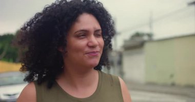 Sıcak bir şekilde gülümseyen bir kadın, rahat bir ifade, kendinden emin, neşeli bir an, pozitif enerji, kendine güven, mutluluk, memnuniyet, dostça bir davranış.