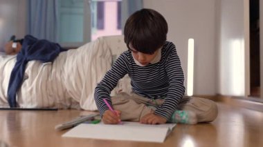 Çocuk, rengarenk bir yapıya dikkatlice bir blok ekliyor. Yaratıcı oyun ve problem çözme işine dalmış, rahat bir ev ortamında eğleniyor.