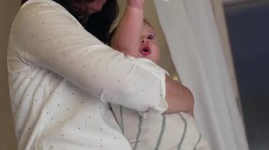Anne bebeğini banyodan sonra havluya sardı. Kapalı ve besleyici bir an. Samimi bir evde bakım yapmanın özgün ayrıntıları.