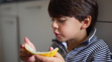 Çocuk kavun yiyor, odaklanmış bir ifadeyle bir ısırık alıyor, sağlıklı bir atıştırmanın tadını çıkarıyor, mutfağa yakın çekim yapıyor, beslenme üzerine vurgu yapıyor, sağlıklı yaşam tarzı için taze meyve seçimi yapıyor.