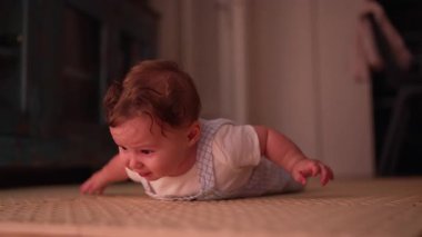 Bebek karın boşluğunda aşağı bakıyor, hareket ve çevreyi keşfetmeye odaklanıyor, erken gelişim kilometre taşı, rahat ev ortamında doğal oyun