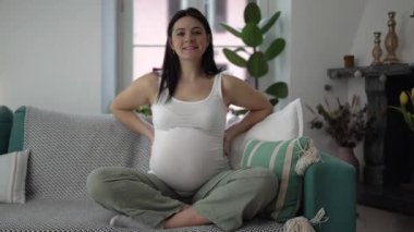 Kadına olan annelik sevgisi doğmamış bebeğe şefkat gösterir. Evdeki koltukta oturmuş karnını okşar.