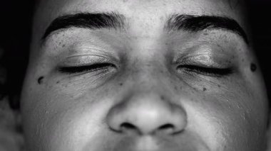 Sessiz meditasyonda gözlerini kapayan genç bir siyahi kadının makro yakın çekimi. Afrika kökenli 20 'li yaşlarda dinleniyor.