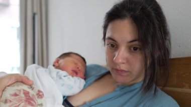 Anne, yeni doğmuş bebeğini yatakta tutarken dizüstü bilgisayarını kullanarak ebeveynliği ve uzaktan çalışmayı dengeler. Modern anneliğe adanmışlık ve çoklu görev