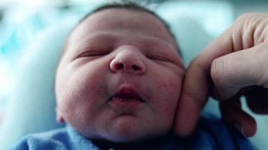 Huzurlu, yeni doğmuş bir bebeğin yüzü, huzurlu bir şekilde uyuyor, bir bebeğin ilk günlerinde annesinin eli tarafından okşanıyor, hassas özellikleri ve sakinliği. 