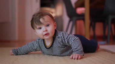 Bebek mindere uzanıyor, kollara dayanıyor, garip ifade, çevreyi keşfetme, gelişim göbeği aktivitesi, ev içi ortam, erken motor becerilere odaklanıyor.