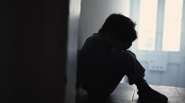 Küçücük bir koridorda yalnız oturan depresif çocuk, Eller Yüzü Kapalı, Üzüntü ve Üzüntü Yansıtan Aile ortamında. 5 yaşındaki çocuk aile kriziyle boğuşuyor.