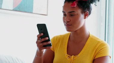 Genç siyahi bir kadın cep telefonu cihazında olumlu uyarı mesajını kutluyor. Afro-amerikalı samimi insan mutlu olmak için elini kaldırdı.