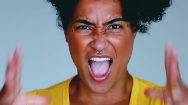 Hüsrana uğramış, güçlü memnuniyetsizlik gösteren genç bir kadın, kamera karşısında yüzünü ekşiten, üzgün ifadeye yakın çekim, ağzı açık, öfkeli eller.