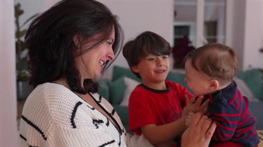 Anne gülümseyen bir çocuk bebeğe sarılırken, neşeli bir aile anı içerideyken, kardeşler kahkahalarla kaynaşırken, içten bir bağ kurarken, anne-çocuk ilişkisi kurarken.