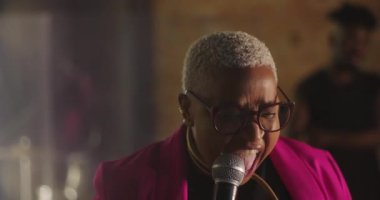 Afrika kökenli bir kadın vaaz veriyor. Evanjelik kilise toplantısı sırasında, mikrofon tutarken, güçlü bir varlık gösterirken, cemaate inançla ve yürekten bağlılıkla rehberlik ederken.