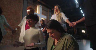 Dua eden kadınlar, eller havada, manevi bir topluluk oluşturuyorlar, birbirlerini destekliyorlar, kilise hizmetinde inanç ve bağlantıyı ifade ediyorlar.