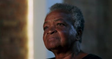 Seyirciler arasında yaşlı bir kadın, ciddi bir ifadeyle, düşünceli bir şekilde uzaklığa bakıyor, düşünceli bir anda yakın plan portresi, dikkat