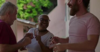 Yaşlı bir adam, neşeli bir zenci kadın ve genç bir adam canlı bir açık hava toplantısında dans ediyorlar, çeşitlilik, neşe ve toplumsal bağ sergiliyorlar.