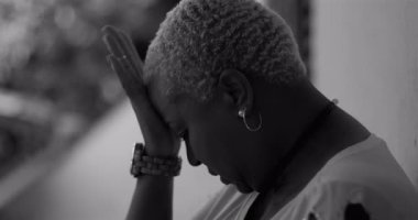 Afro-Amerikan kadın başını eğiyor, yüzünü çaresizlik ve hassasiyet jesti ile kapatıyor, pişmanlık, pişmanlık, depresyon ve akıl hastalığı gibi duyguları yansıtıyor.