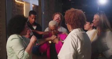 Çeşitli insanlar, pembe ceketli, Latin kökenli Latin bir kadının etrafında toplandı. Manevi bir ortamda birlik, inanç ve duygusal bir bağ kurdular.