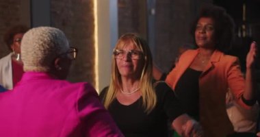 Bir dua grubunda gülümseyen kadın, dans ediyor ve başkalarıyla el ele tutuşuyor, farklı, destekleyici bir toplulukta ruhani bir sevinç, inanç ve bağlantı anı paylaşıyor.