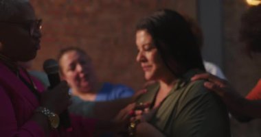 Çeşitli bir dua grubunda gülümseyen kadın, inanç, iyileşme ve duygusal bağlantıyı vurgulayan ruhani bir toplantıda destek ve cesaret alıyor.