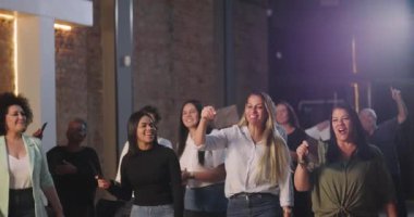 Kiliseye ibadet sırasında bağış kutusuna zarf koyan iki kadın, neşeli ve saygılı ifadeler, ruhani sunuma katılan çeşitli arka planda yer alan farklı topluluk