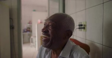 Afrika kökenli yaşlı bir adam fayanslı mutfakta neşeyle gülüyor, mutluluğu ve bağlantıyı ifade ediyor, sıcak bir yuva ortamında her gün samimi.
