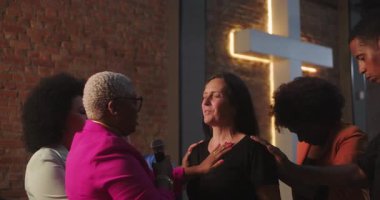 Kapalı gözlü bir kadını çevreleyen çeşitli dua grupları. Duygusal manevi bir inanç ve bağlılık anı. Çapraz bir sembol altında birlik, inanç ve desteği simgeliyor.