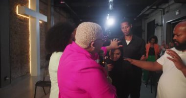 Bir grup insan ruhani namaz kılıyor. Odaklanmış bir kadına dokunuyorlar. Bağlantı ve yetkilendirmeyi vurguluyorlar.