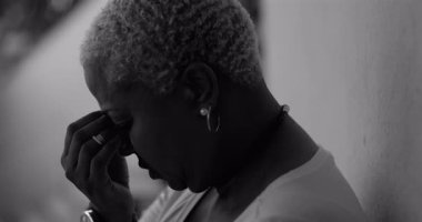 Afrika kökenli Amerikalı bir kadının derin duygusal karmaşa içinde yüzünü tek eliyle kapatması, üzüntü, pişmanlık, depresyon ve hassasiyet duygularını ifade etmesi, siyah beyaz