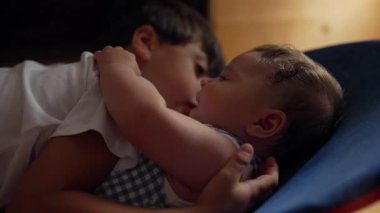 Küçük çocuk bebek kardeşe yakın yatıyor, sevgi dolu kardeş bağı, samimiyet ve sevgi, nazik aile anı, çocukluk bağı, yakın ve hassas etkileşim