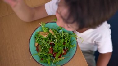Makarna salatası yiyen gencin genel bakış açısı, taze malzemeler, sağlıklı yemek, çocuk beslenmesi, nötr reaksiyon, evde yemek yeme konusunda çatal tereddüt.