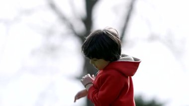 Çocuk parkta pembe bir topla oynuyor, aktif açık hava oyunu, dinamik hareket, spordan keyif alma, enerjik aktivite, canlı doğa sahnesi, gençlik eğlencesi.