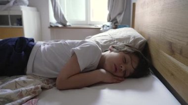 Çocuk tek başına uyuyor, huzur içinde kıvrılıyor, rahat ve güvenli bir uyku alanının huzurlu ve sakin ortamını vurguluyor, yumuşak sabah ışığıyla.