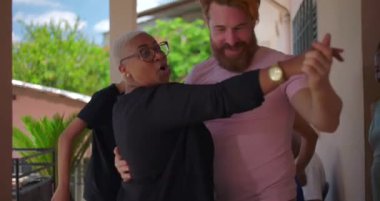 Farklı geçmişlerden gelen erkek ve kadın bir açık hava kutlaması sırasında aile ve arkadaşlarıyla neşeyle dans ediyor, bağları kucaklıyor ve çok kültürlü bir uyum içinde.