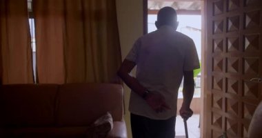 Yaşlı bir adam elinde bastonla verandaya çıkıyor. Bağımsızlığı, dayanıklılığı ve sakin bir evde dışarıyla olan bağlantıyı simgeliyor.