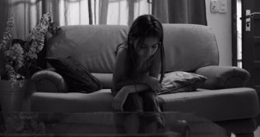 Koltukta oturan genç bir kız, içine kapanık ve izole bir şekilde, hüzün, çocukluk depresyonu, yalnızlık ve duygusal mücadele belirtileri gösteriyor.