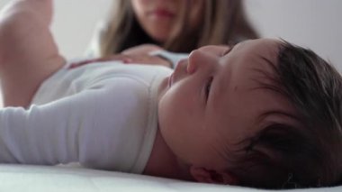 Bebek yatakta uzanıyor, geniş gözlerle çevreyi merakla izliyor. Rahat atmosfer, çocukluğun masumiyetini ve mucizesini yakalar.