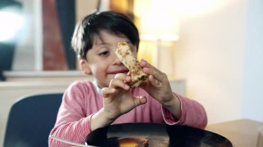 Çocuk pizza yiyor, dilime merakla bakıyor, çocukluk yemeklerinin basit zevklerini temsil ediyor.