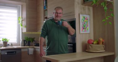 Sıcak içeceğe, kahveye ya da çaya tepki veren bir adam. Düşünce anı, gündelik mutfak düzeni, modern iç mekan, ev içi aktiviteler, evde kişisel zaman geçirme.