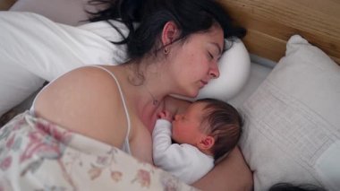 Anne, yeni doğmuş bir bebekle yatakta huzurlu bir şekilde uyuyor. Bağlanma ve dinlenme anı. Doğum sonrası dinlenme, annelik bakımı ve erken annelik, huzurlu bir atmosfer.