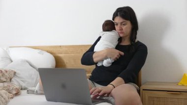 Yeni doğmuş bir bebeği kucağına alarak ve dizüstü bilgisayarla çalışarak, ebeveynlik ve uzak işleri dengelemek, adanmışlığı, aşkı ve aile sorumluluklarını vurgulayarak odaklanmış bir anne.