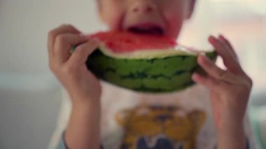 Çocuk sulu bir dilim karpuzun tadını çıkarıyor, yüzüne yakın çekim, yaz meyvesi, sağlıklı atıştırmalık, ferahlatıcı ikram, ev içi doğal ışık, tatlı karpuzun tadını çıkaran genç çocuk.